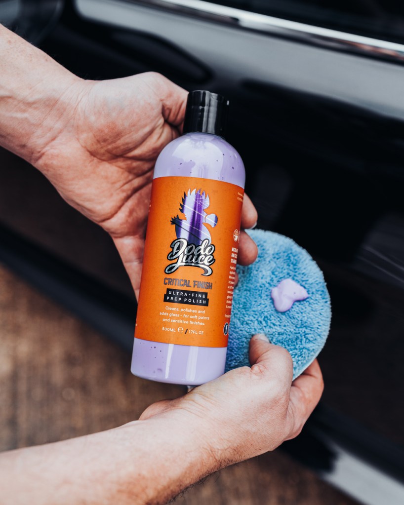 man holding bottle of car polish and applicator pad ready to apply to a car