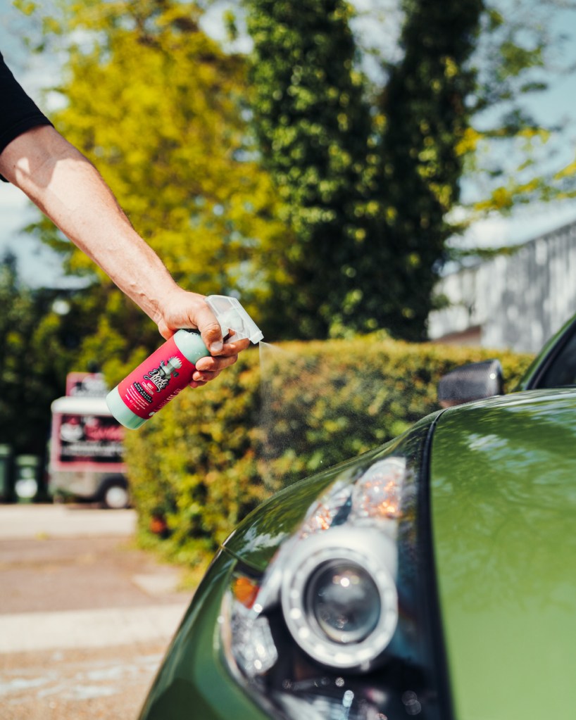 man spraying a car bonnet with quick detailer spray